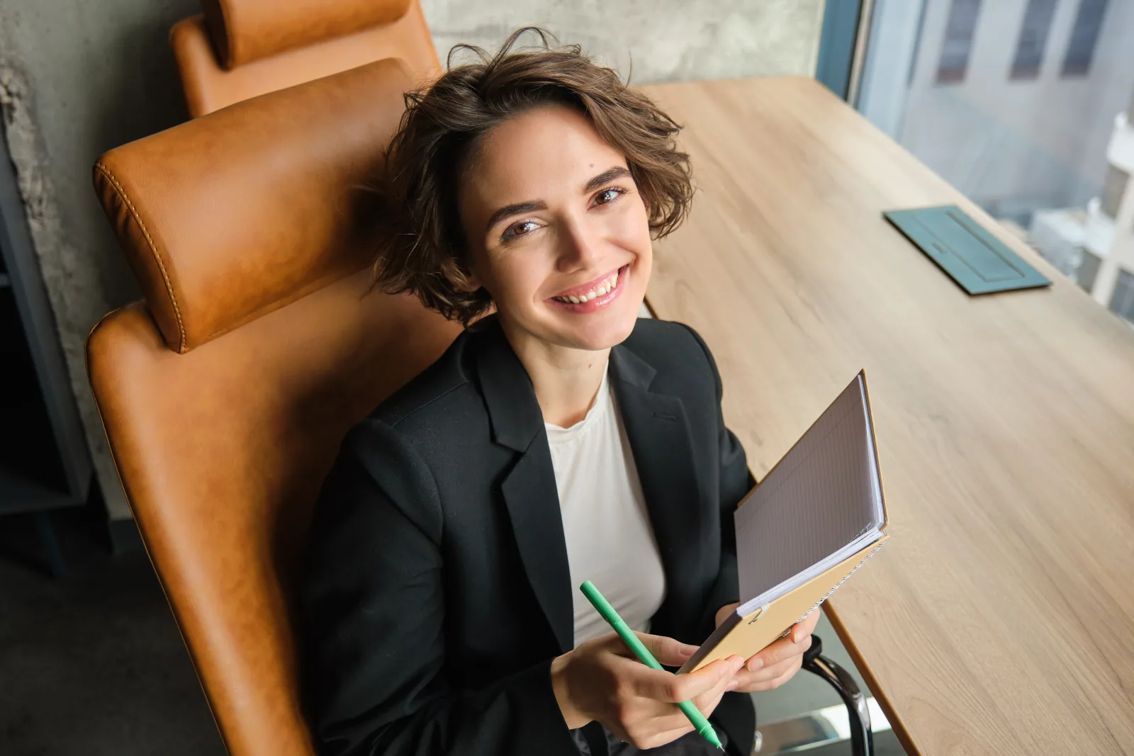 Frau mit Notizbuch und Stift an ihrem Arbeitsplatz