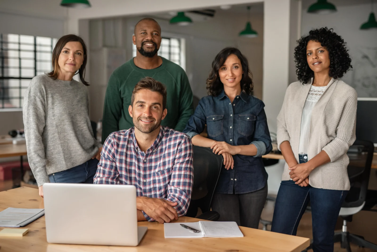 MBA Fernstudium für Berufstätige - Team im Büro Fünf Personen in einem Büro, gemeinsam an einem Laptop.